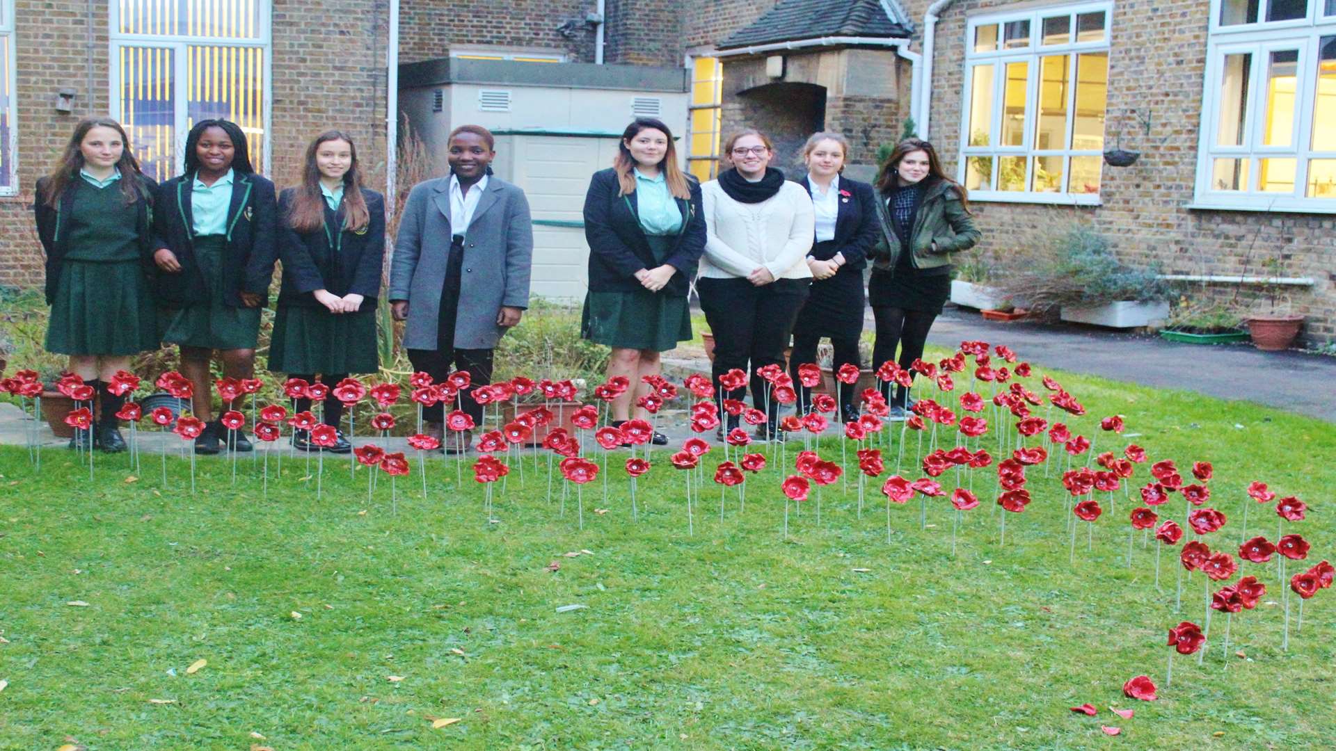 Ruby Taylor, Eseohe Lawrence-Orumwense, Moyra Donnelly, Eliza Sapara-Grant, Alana Cowdery-Brewster, Katie-Ann Hill, Kitty Tucker and Willow Wilkins in front of Dartford Grammar School for Girl's display of ceramic poppies.
