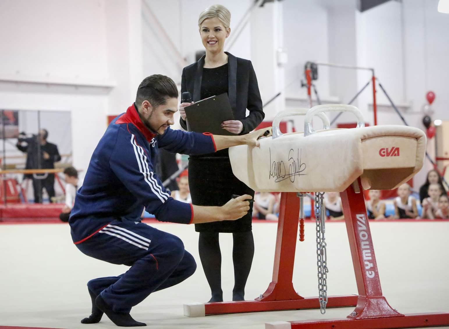 Louis Smith signs the pommel horse on which he won silver at the European Championships in Glasgow watched by Chantelle Harman, NDGA Operations Manager