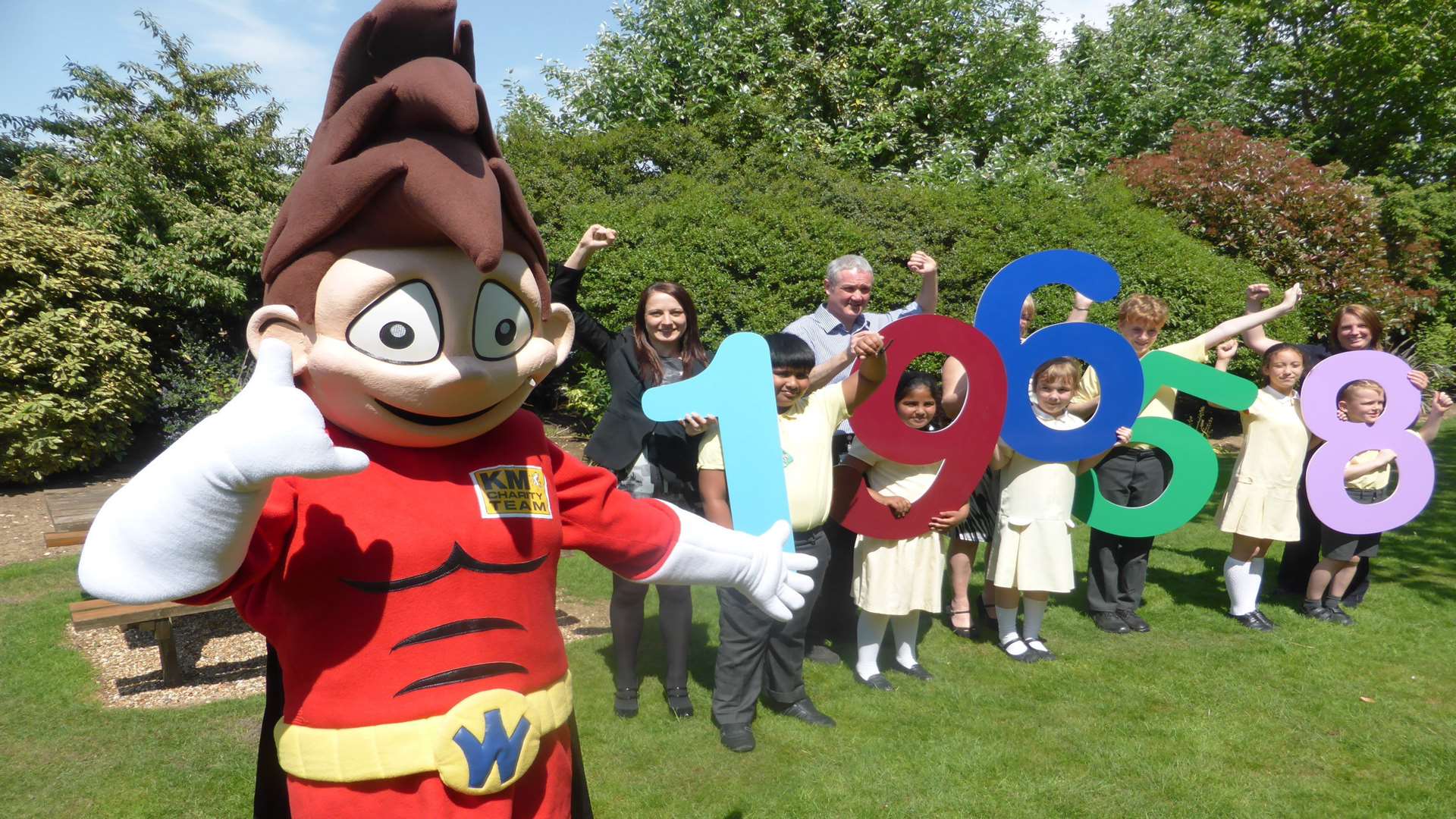 Pupils from St Francis' Catholic Primary School, Maidstone join KM Walk to School mascot Wowzer, partners and sponsors to announce the number of school run car journeys removed from Maidstone roads so far this academic year.