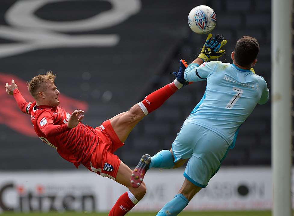 Gillingham's Liam Nash wins a penalty after a challenge with the MK Dons keeper Picture: Ady Kerry