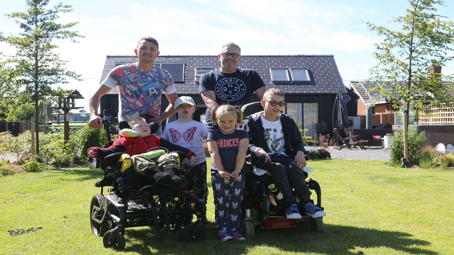 L/R: Kyle Ratcliffe with Garry, with children, Curtis, six, Bella, 10, Phoebe, five and Haydn in their garden of the home DIY SOS built in Minster