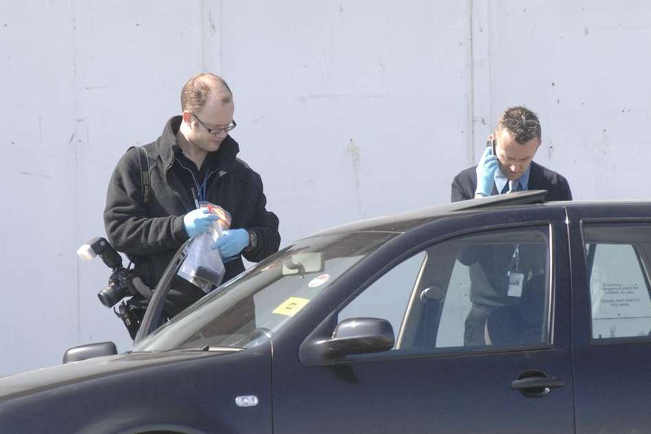 Police photograph a black VW Golf at the scene