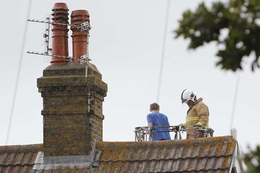 A firefighter talks to the young man on the Sittingbourne roof. Picture: Matthew Walker