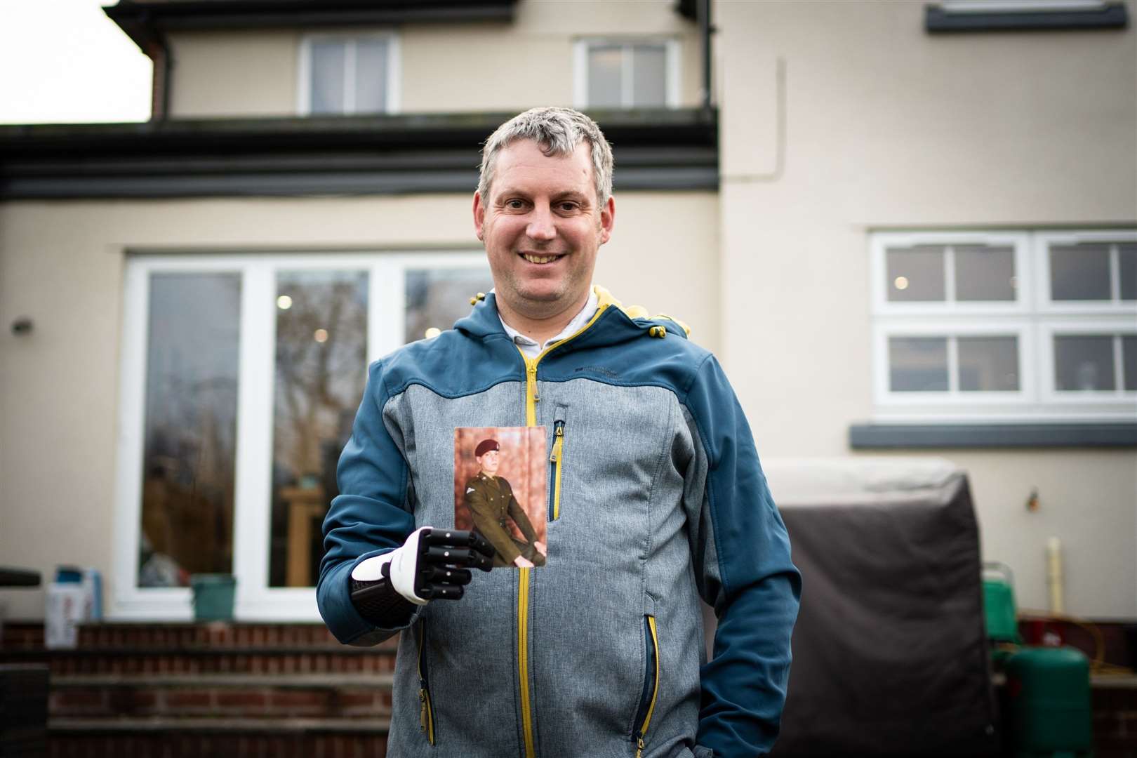 Darren Fuller's bionic 'Hero Arm' holds a photo of himself from his days in the army. Picture: SWNS