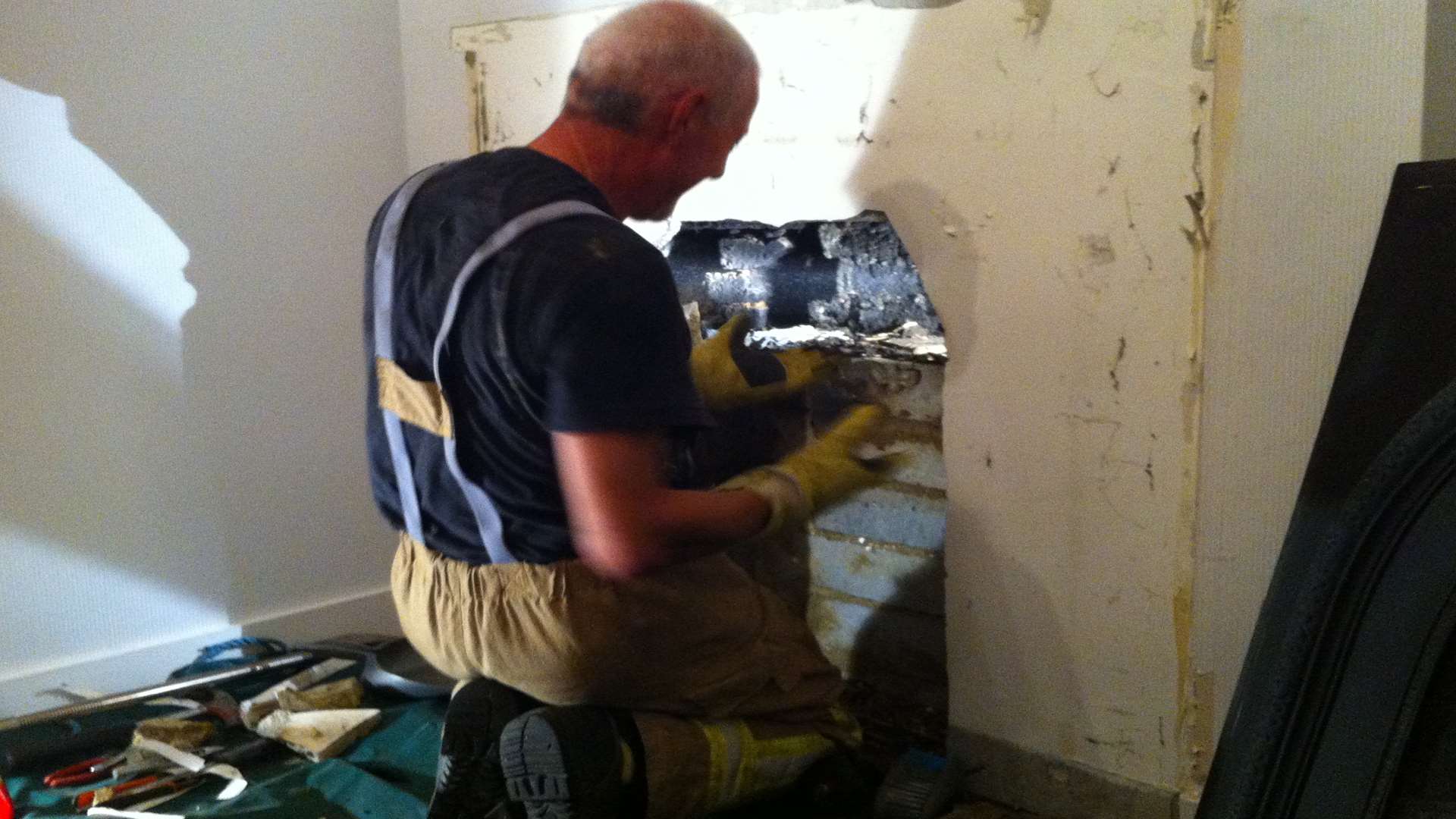 A firefighter dismantles the fire surround to reach Frank the cat