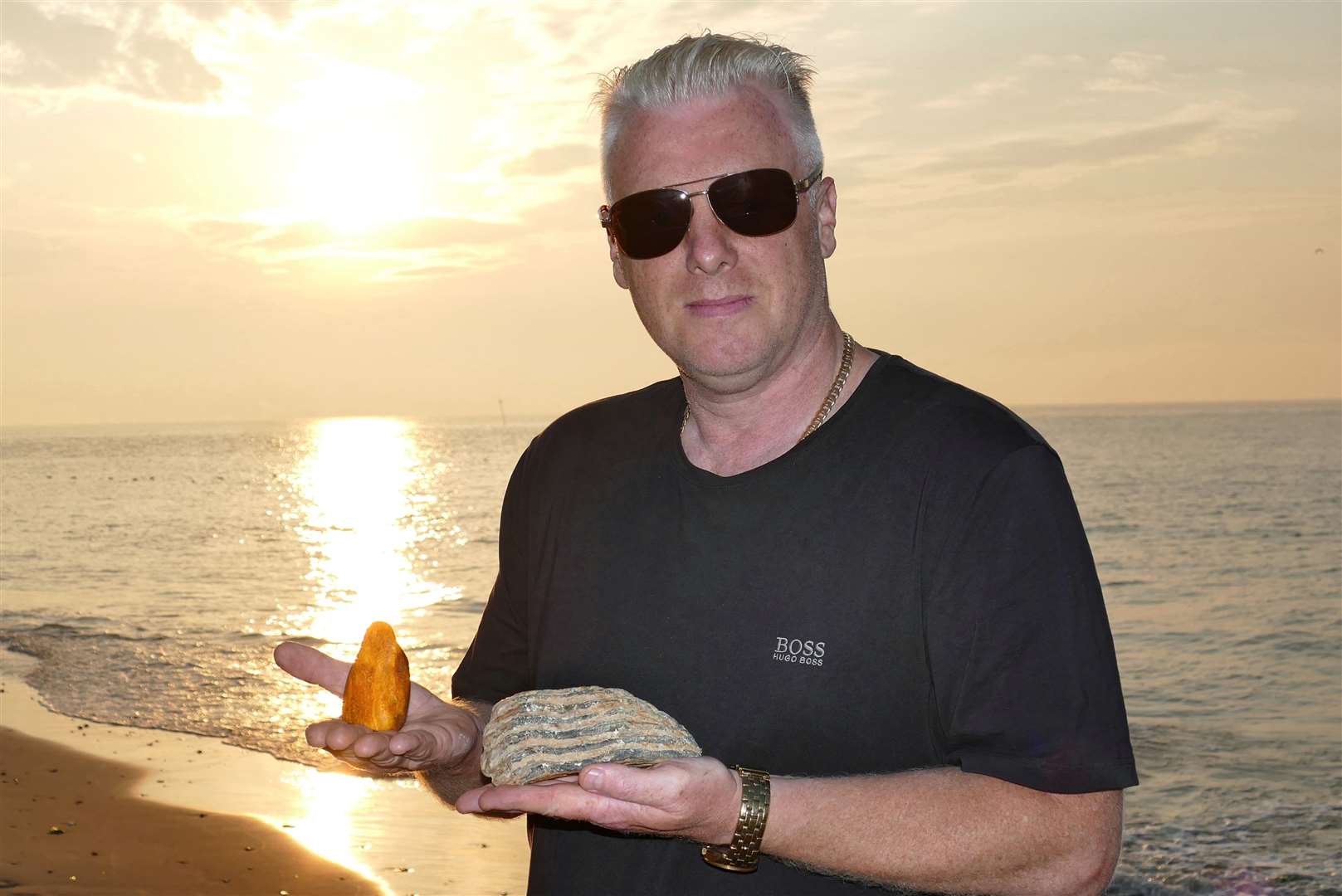 Frank Leppard has been beachcombing on Kent's shores since he was a little boy. Here he is with two of his prize finds - a mammoth tooth, and a huge piece of amber. Picture: Frank Leppard