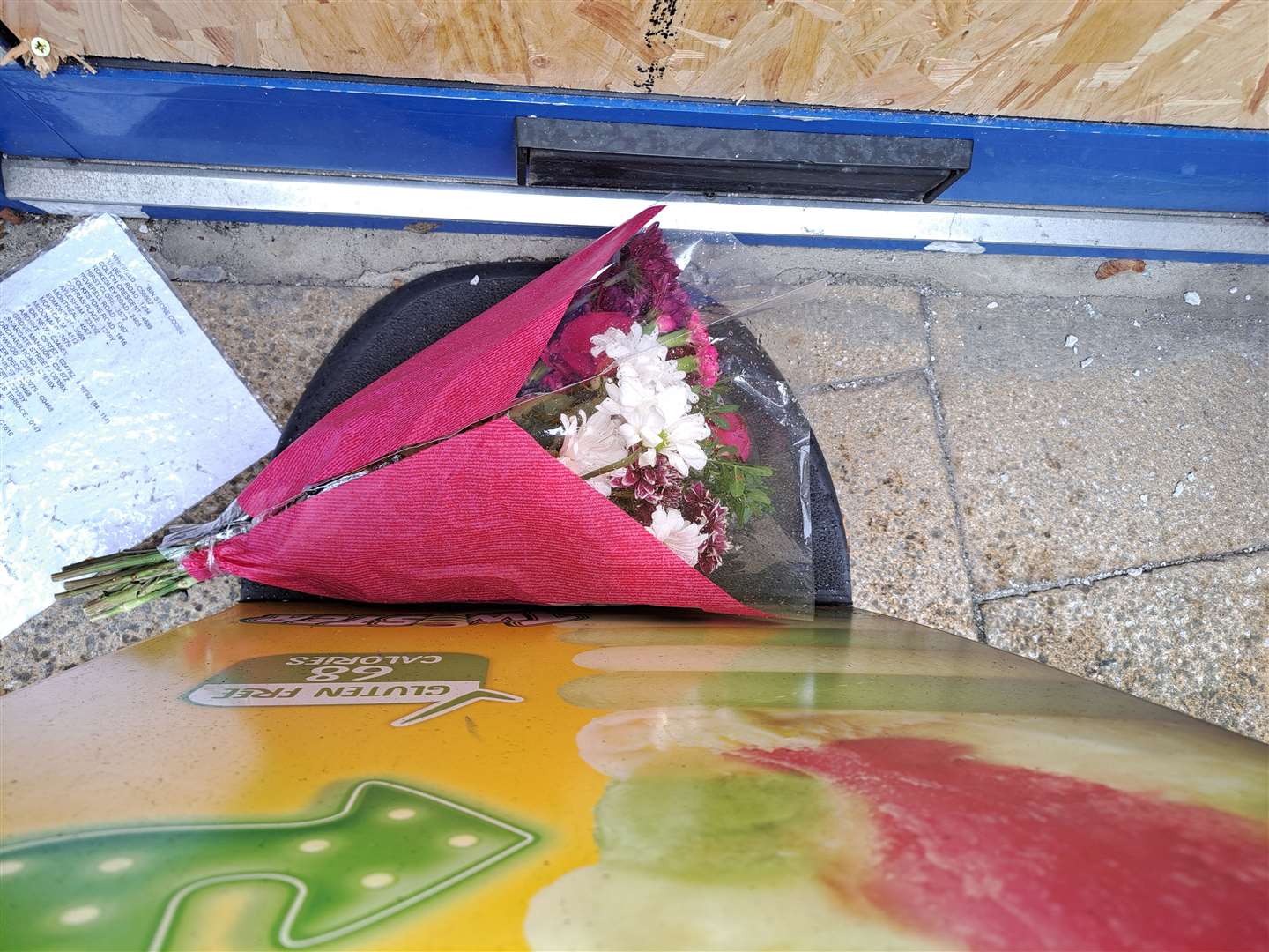 Flowers have been placed behind a sign at the entrance to Thenu Convenience Store in Snargate Street, Dover after an attack over the weekend