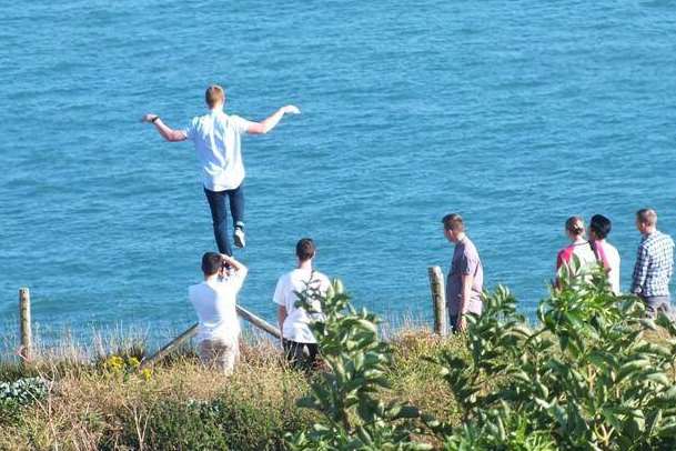 The youth teeters over a cliff edge in a reckless stunt