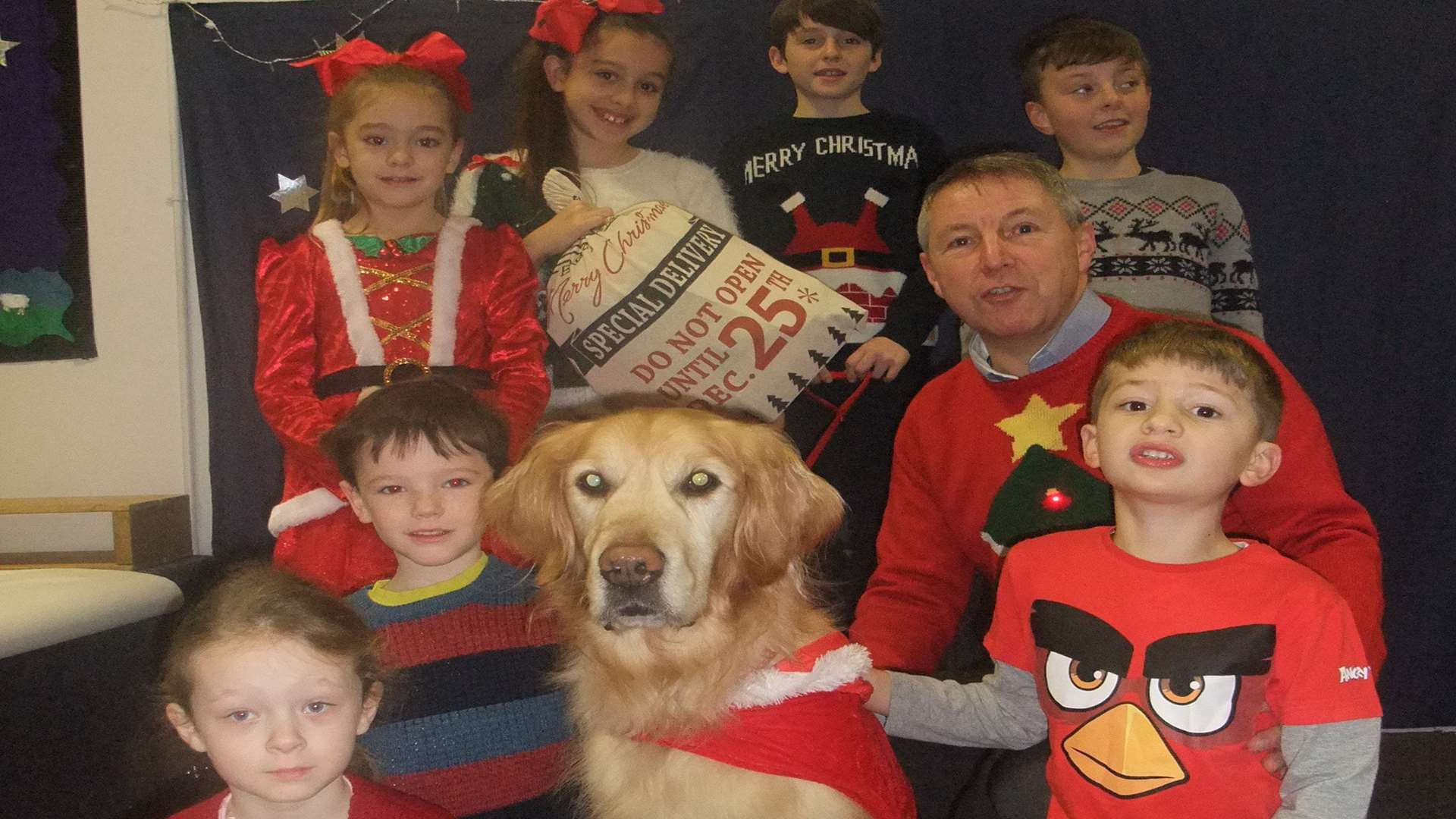 Buddy, the five-year-old golden retriever, with St Ethelberts Catholic Primary School head teacher John Letts and some of the children