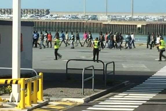 Passing bemused holiday-makers, the illegal immigrants are taken away. Picture: Mark Salt