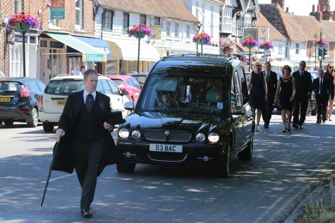 The funeral procession proceeds along the High Street