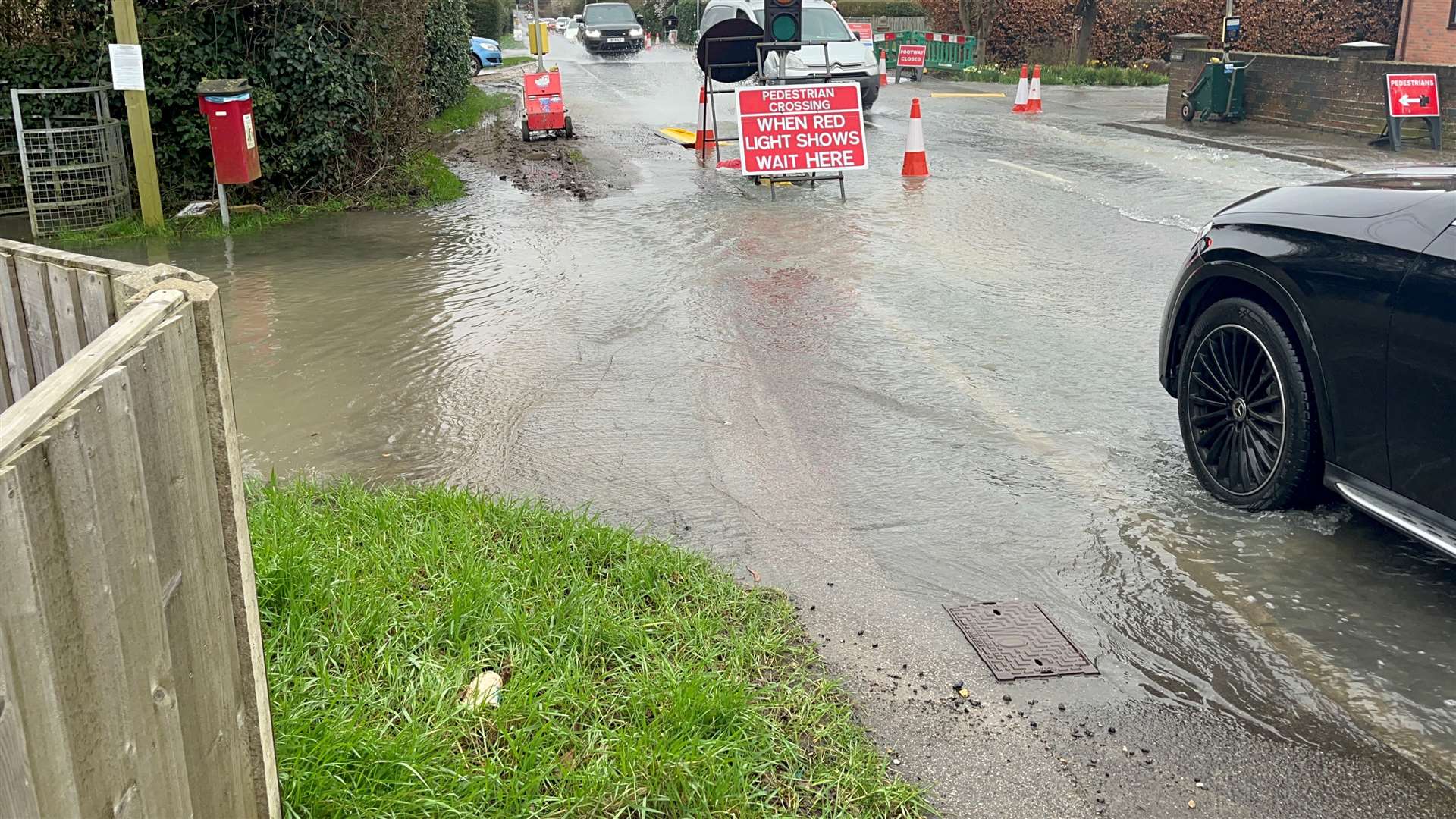 There are two-way traffic lights set up in Ashford Road with cars having to drive slowly through the deep water