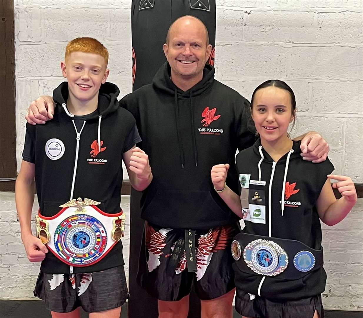 The Falcons Kickboxing Club head coach Mark White, centre, with their new junior world champions, Aston Young, 14, and 12-year-old Cleo Musslewhite
