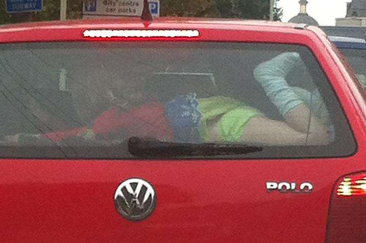 Girl sprawled across parcel shelf in back of moving car