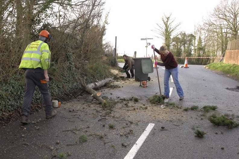 Residents and a KCC employee clear a fallen tree in Cockering Road, Chartham. Picture: Chris Davey