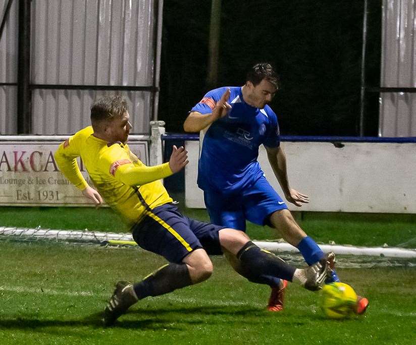 Herne Bay's Dan Johnson clears as Whitstable frontman Harry Goodger puts in a firm challenge during Bay's 2-1 defeat to rivals Whitstable on Tuesday night. Picture: Les Biggs