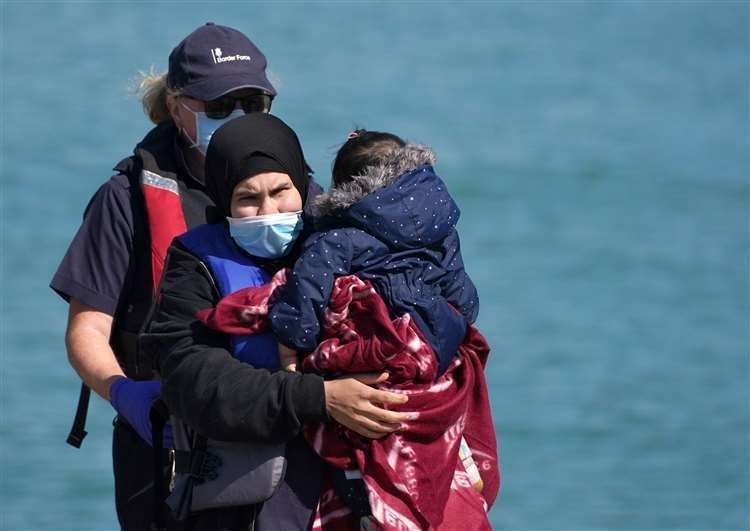 A Border Force officer helps a woman with a young child brought in to Dover. Photo: Steve Parsons/PA
