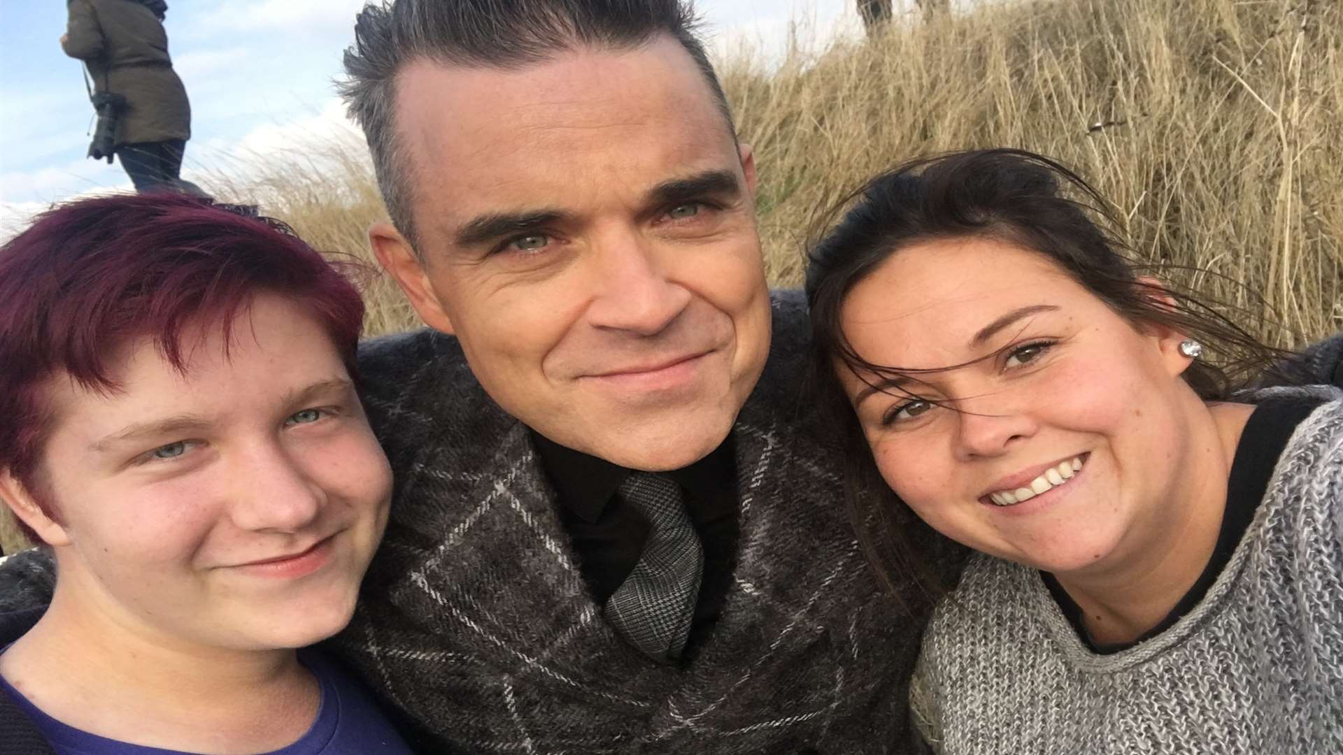 Robbie Williams poses for a selfie with Dan Hughes and Sasha Burgoine at Leysdown, Sheppey, after Sasha crashed her car while trying to see him filming his Christmas video