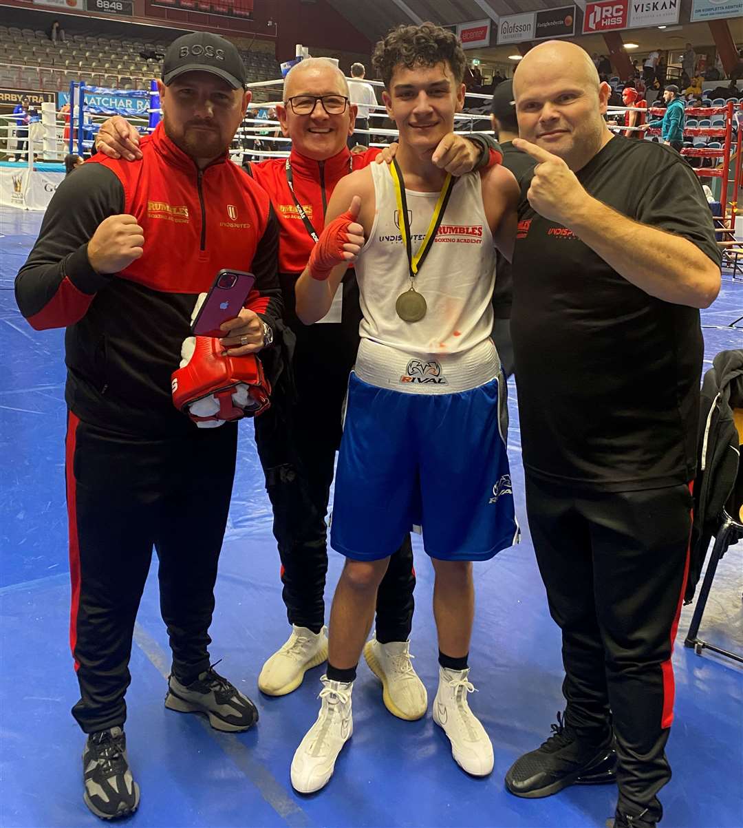Riley Khalid celebrates his gold medal with his coaches in Sweden