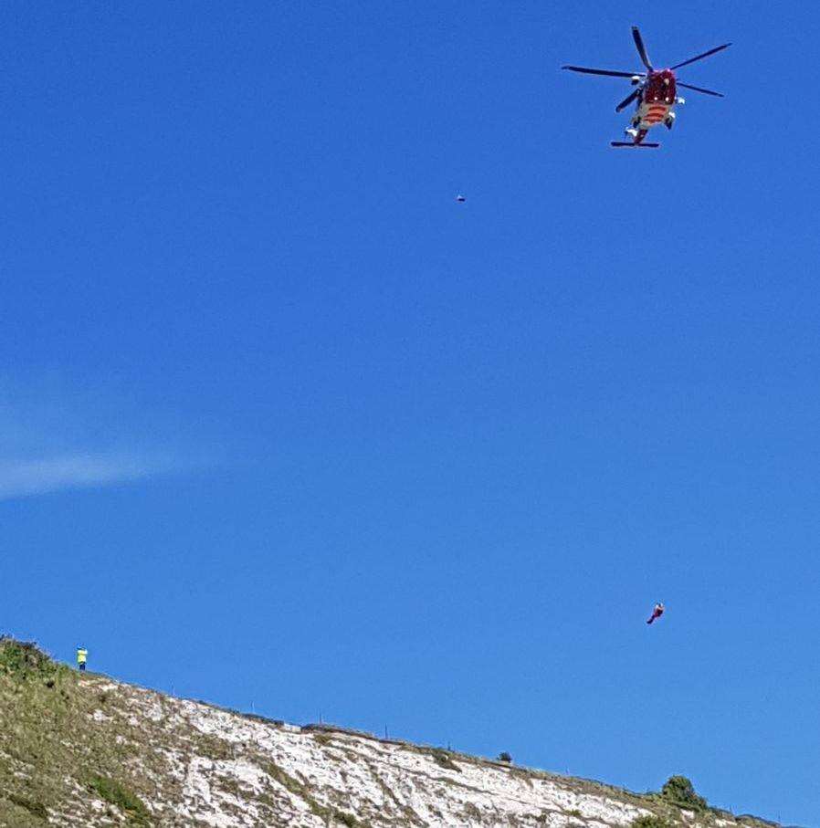 The Coastguard helicopter lowers a winchman to rescue the teenager