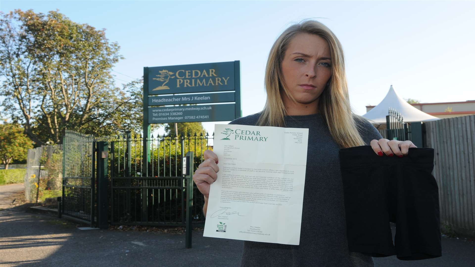 Tara Fifield holds a pair of the controversial shorts and the letter barring her from Cedar Primary