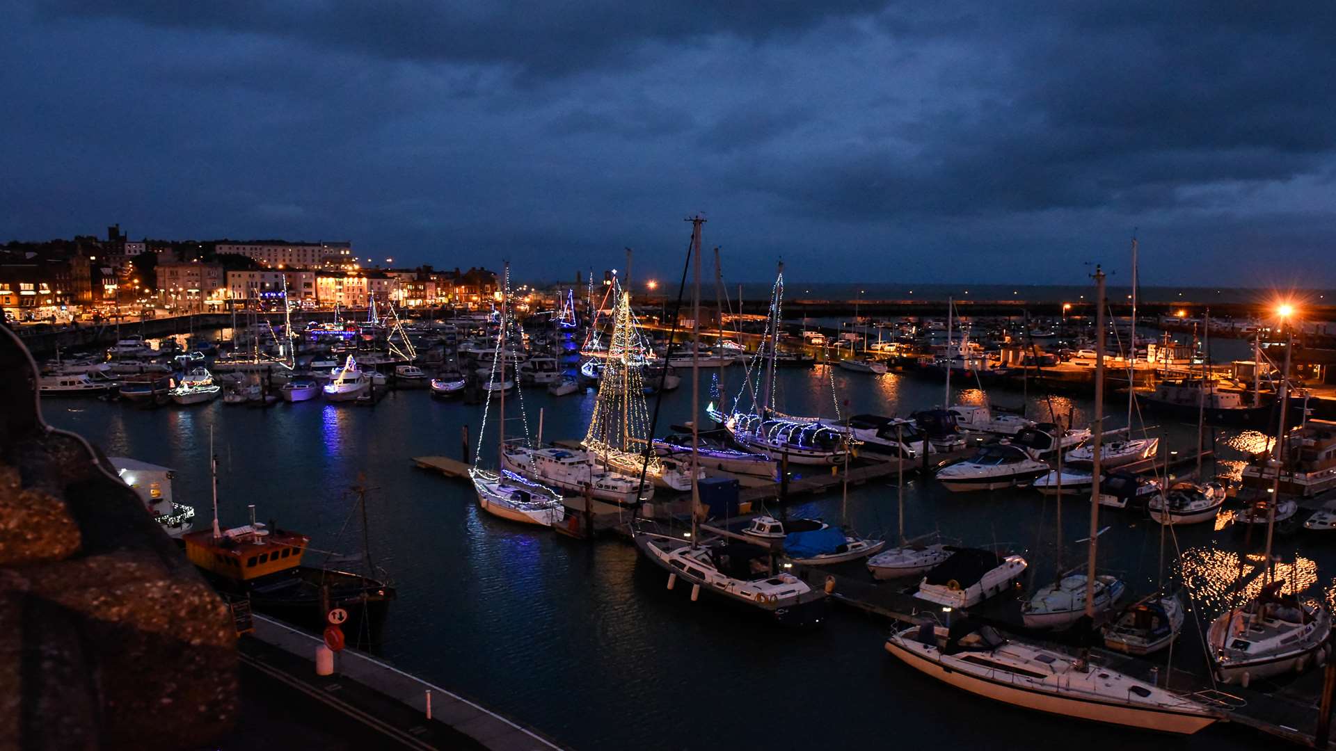 Boats in the harbour and marina lit up with Christmas lights