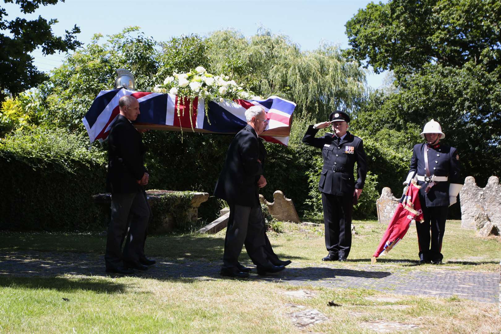 A fire service colour party salutes the coffin