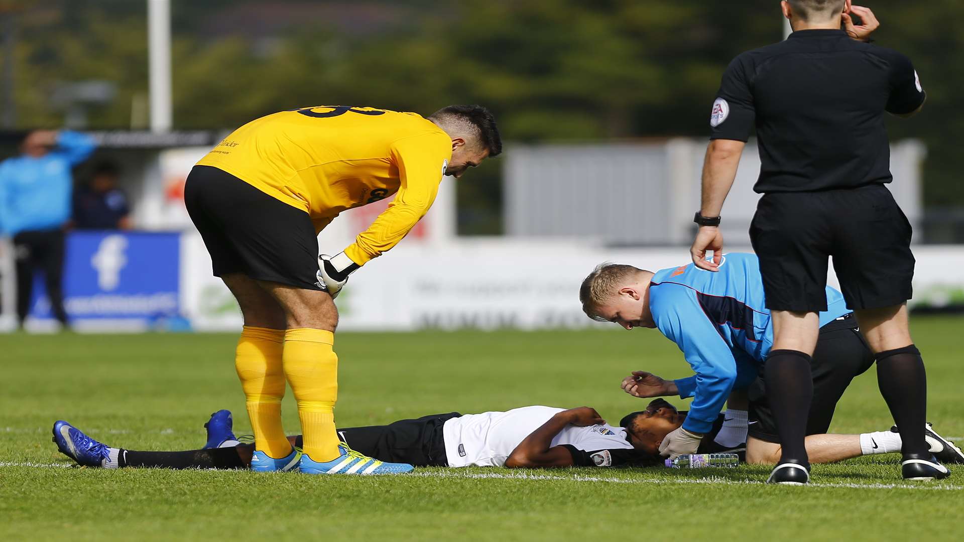 Ricky Modeste needs treatment from Dover physio Callum Green after being by being struck on the head by the ball Pic: Matt Bristow