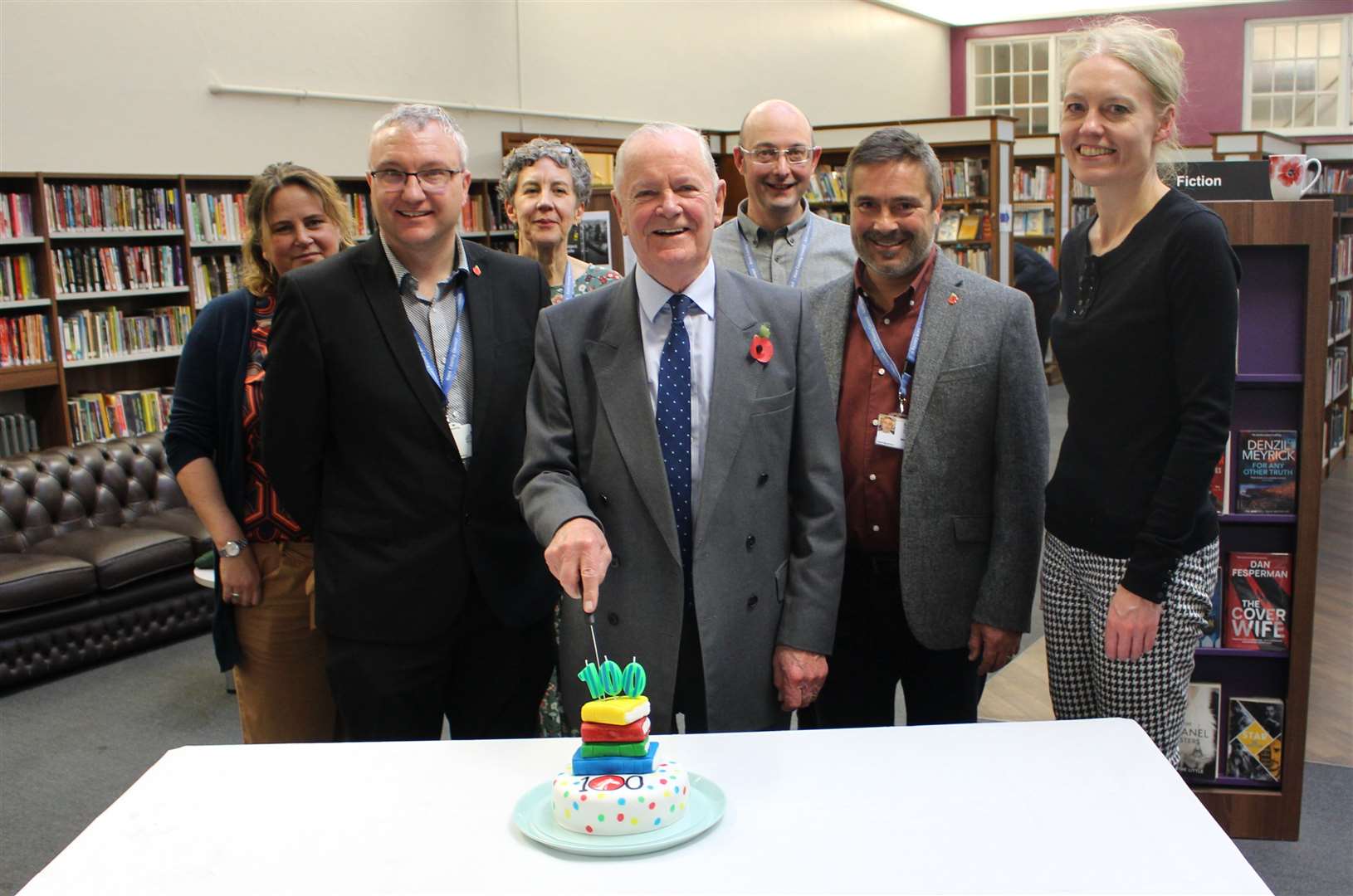 KCC's cabinet member for libraries, Cllr Mike Hill, cuts a celebratory cake to mark the service's 100th birthday, with staff at Dartford library