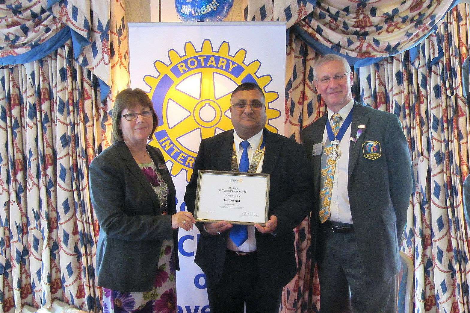 Gravesend Rotary club president Dilbagh Singh (centre) receives a commemorative certificate for the club's 90th birthday