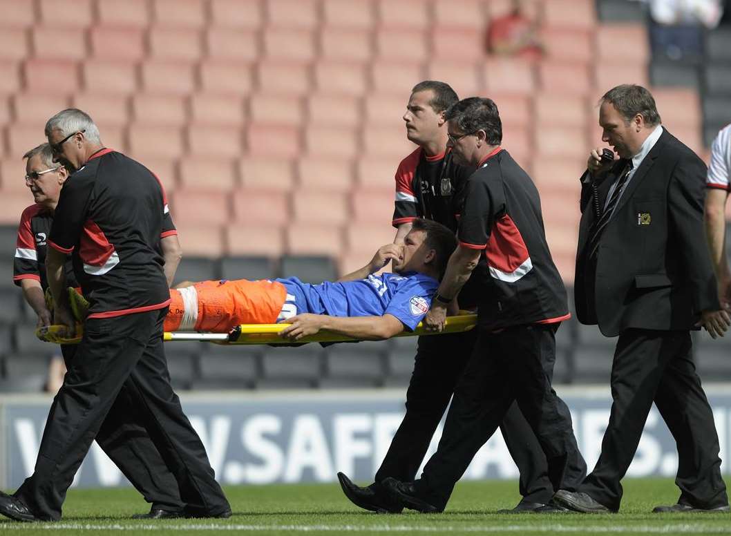 Gills striker Cody McDonald is stretchered off against MK Dons. Picture: Barry Goodwin