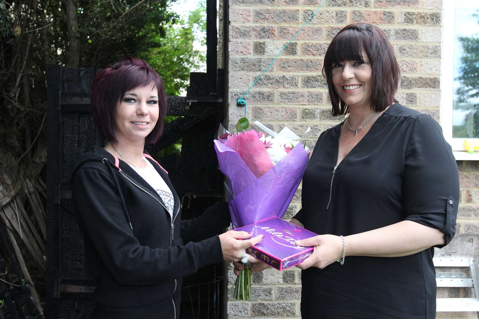 Ruthie Sears presents Laura Hassain with flowers and chocolates for raising the alarm