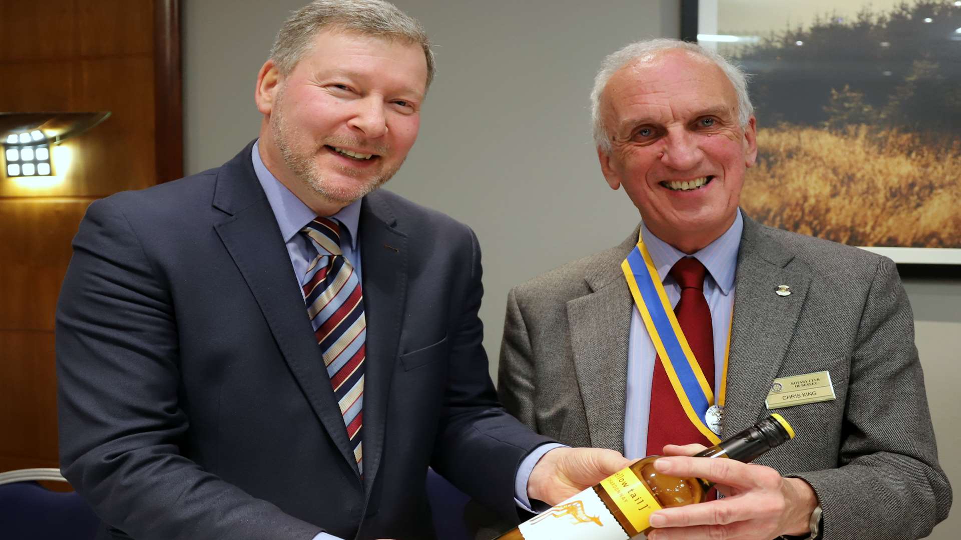 Chris King, President of Bexley Rotary Club, presents a bottle of wine to Simon Dolby of the KM Charity Team.