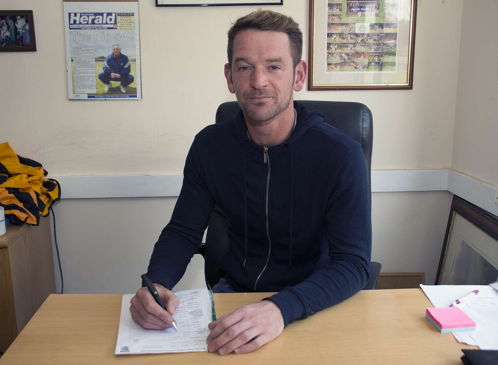 Carl Rook signs his contract in Folkestone manager Neil Cugley's office Picture: Don Linkin