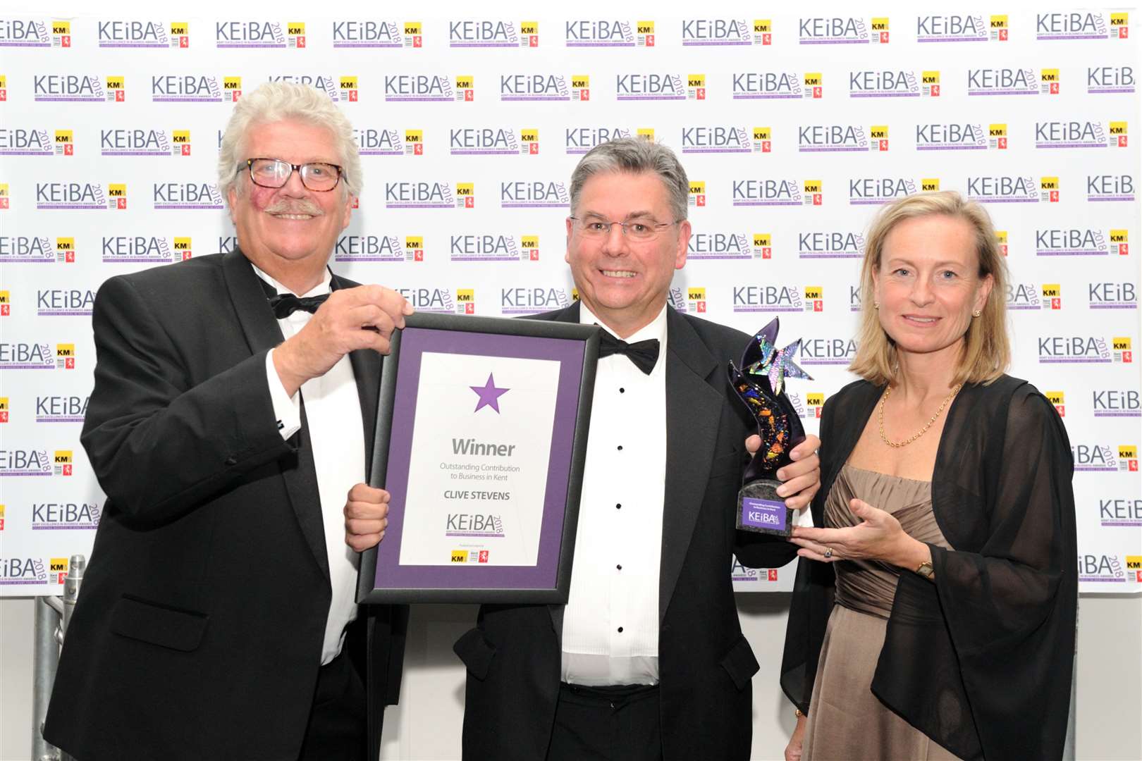 Clive Stevens, centre, wins the Outstanding Contribution to Business Award at KEiBA 2018 - flanked by KCC's Mark Dance, left, and the KM Media Group chairman Geraldine Allinson
