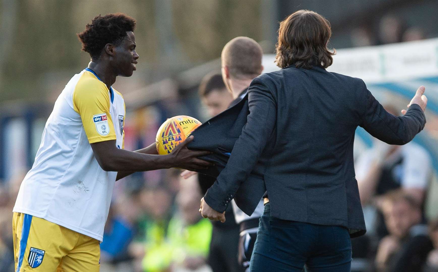 Gills' Leo Da Silva Lopes apears to cheekily dry the ball on Wycombe manager Gareth Ainsworth's jacket Picture: Ady Kerry