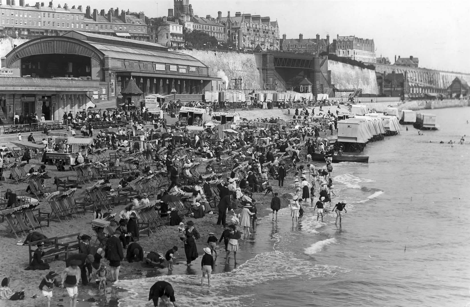 The Ramsgate Harbour station looms in the background as people pack the beach with deck chairs