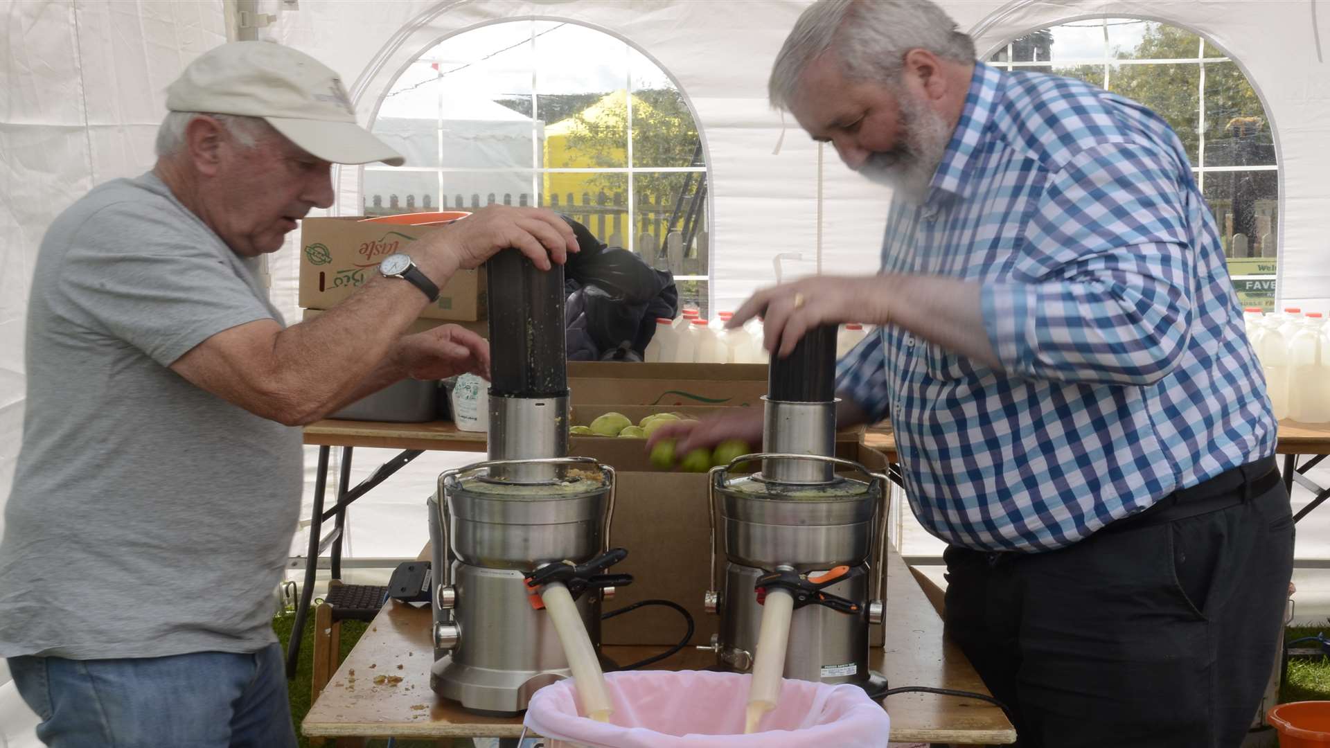 Nebin Stewart and Dick Nevitt use a modern juicer during the apple juicing competition