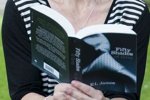 A woman reading Fifty Shades of Grey