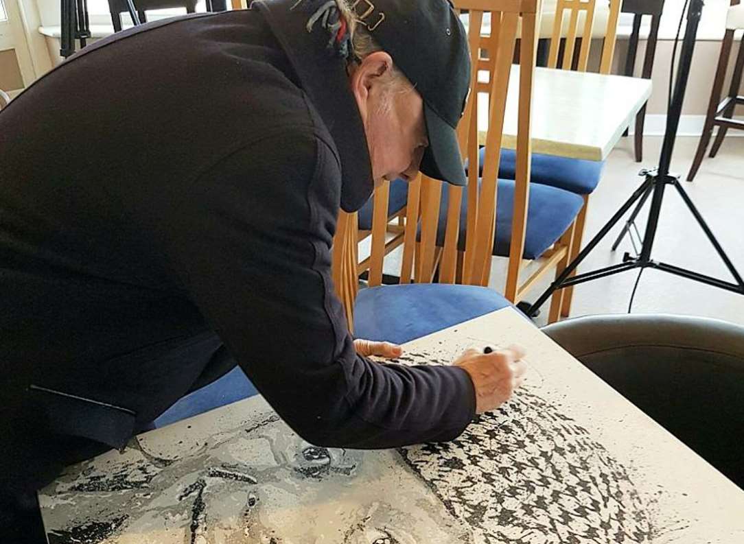 Sir David Jason signing a painting of himself by artist Ben Stokes
