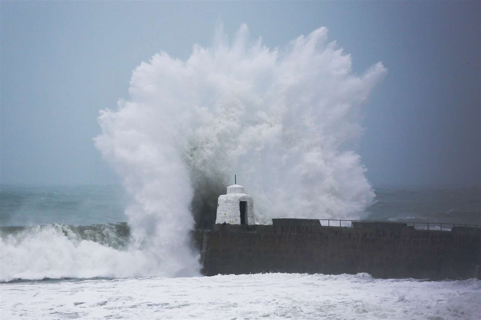 Waves pound against the harbour wall at Portreath in Cornwall in 2020 (PA)