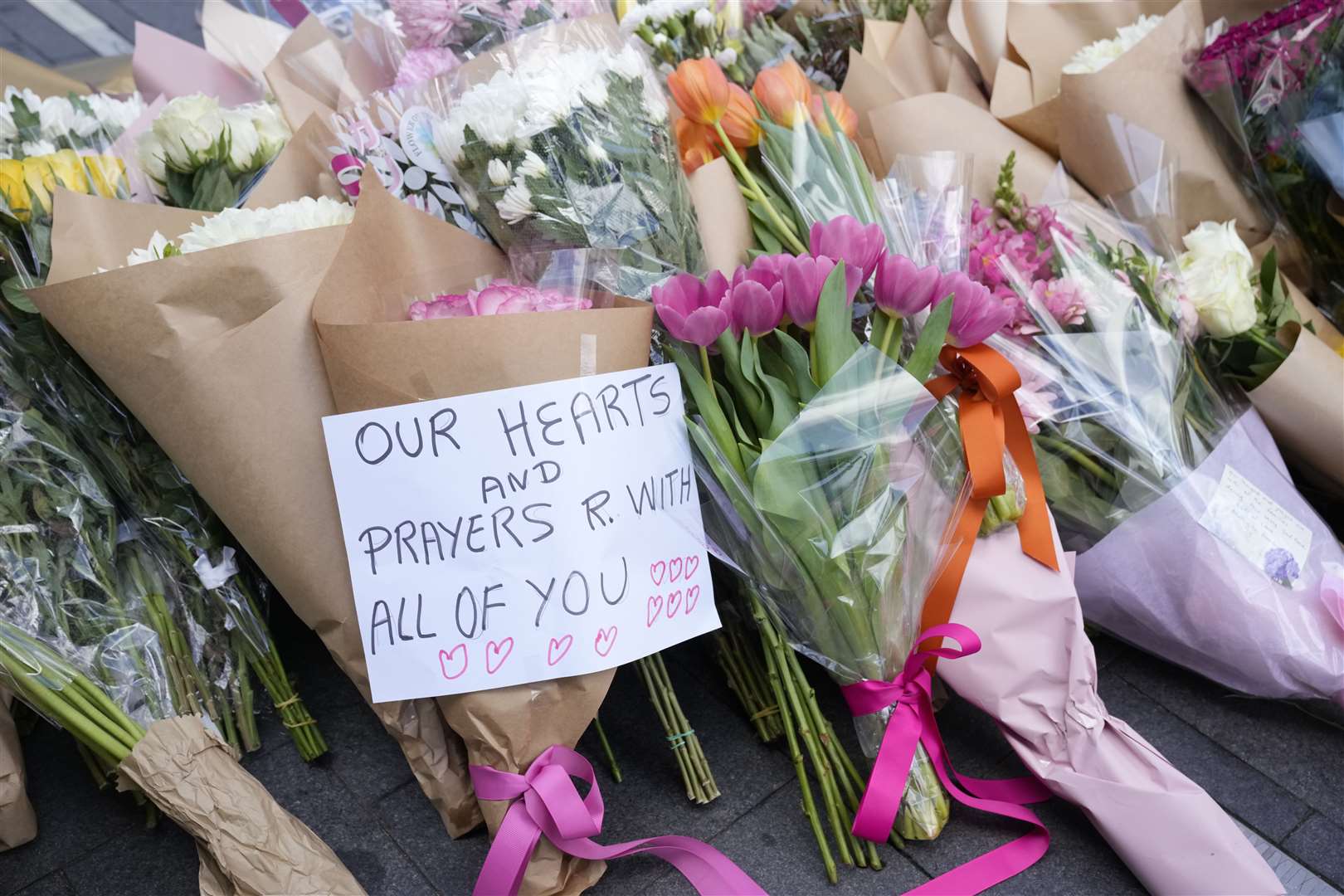 A note is left with flower tributes near a crime scene at Bondi Junction in Sydney (Rick Rycroft/AP)