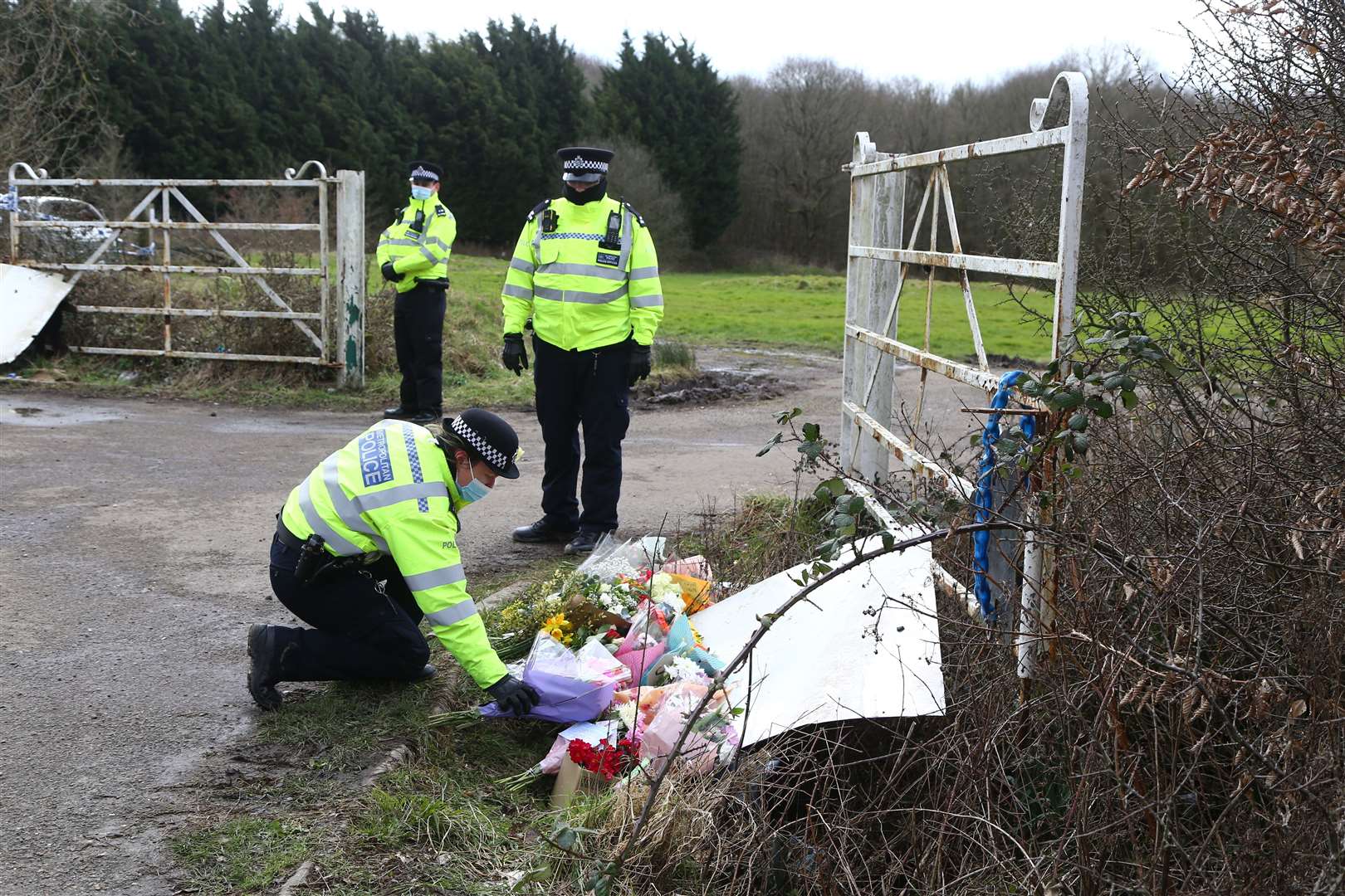 A police officer places flowers left by members of the public at the site as Metropolitan Police continue their search near Great Chart, Kent (Gareth Fuller/PA)