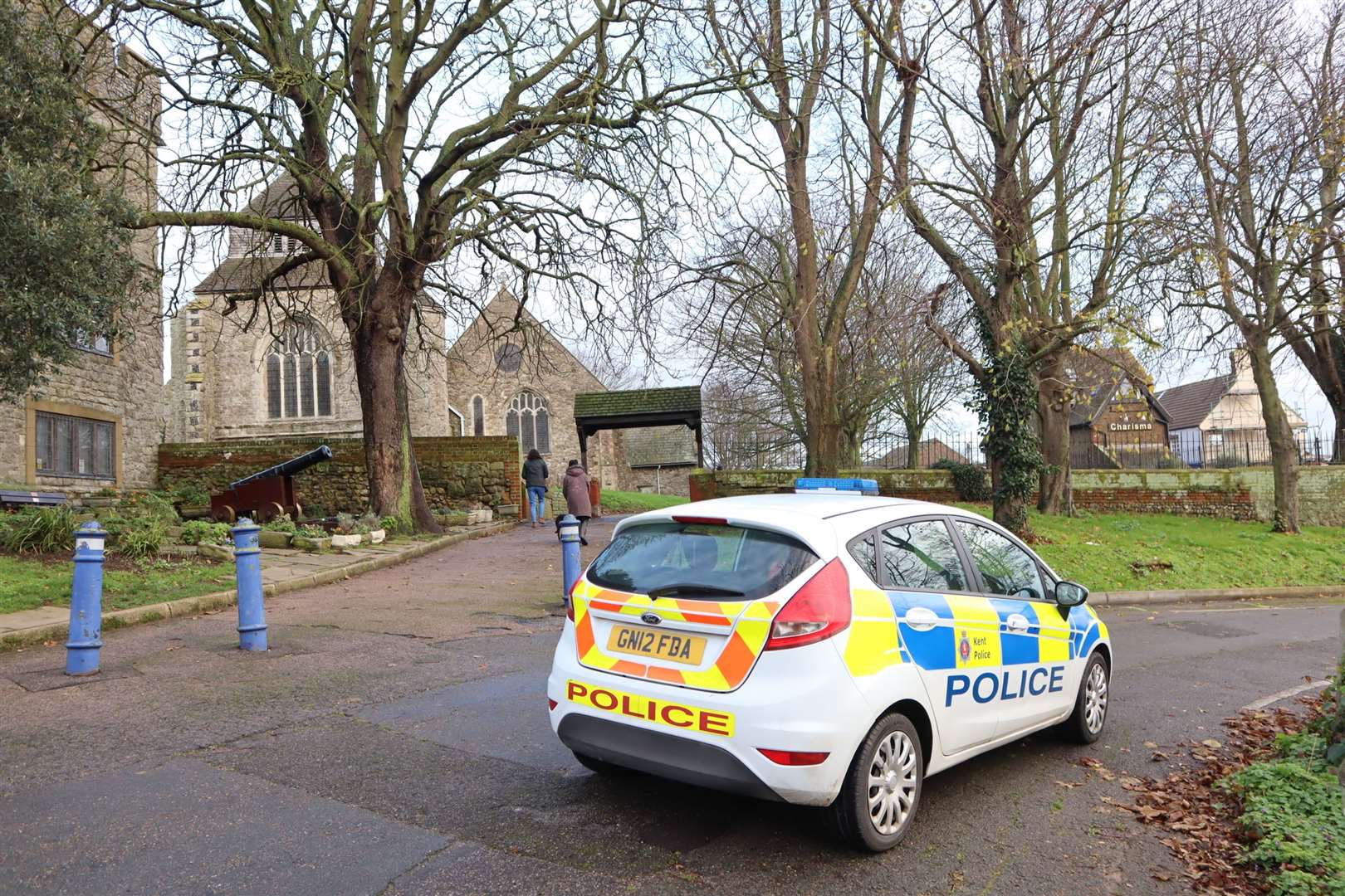 A police car parked near Minster Abbey where a gaping hole has appeared in the graveyard