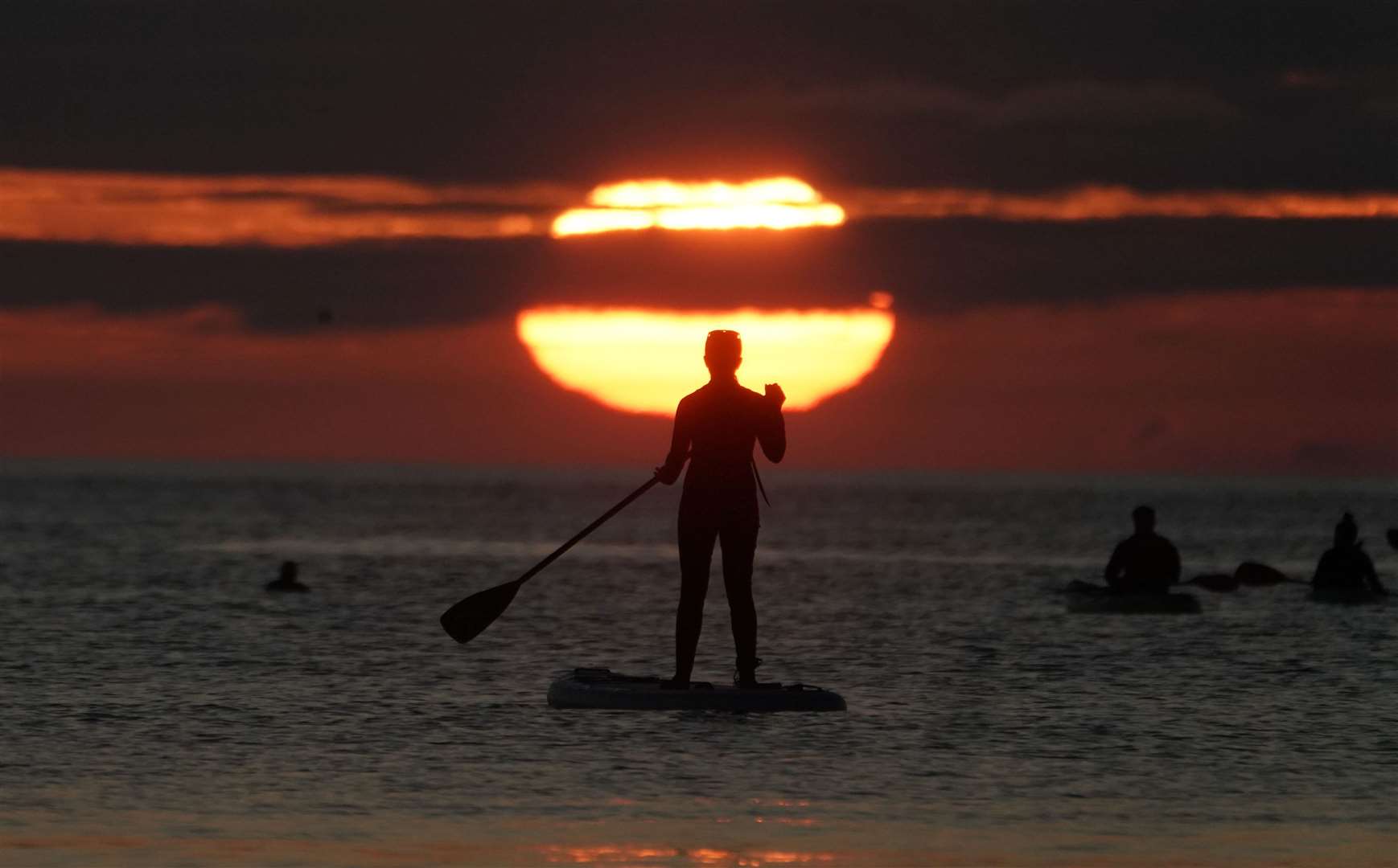 A paddleboarder watches the sunrise at Cullercoats bay in North Tyneside (Owen Humphreys/PA)