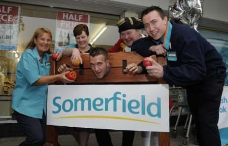 Somerfield duty manager Graham Birkett is put in the stocks at the store opening by his colleagues and is threatened with fruit, from left, Michell Bear, Lindsey Mannering, Ian Jones and Paul Marsh