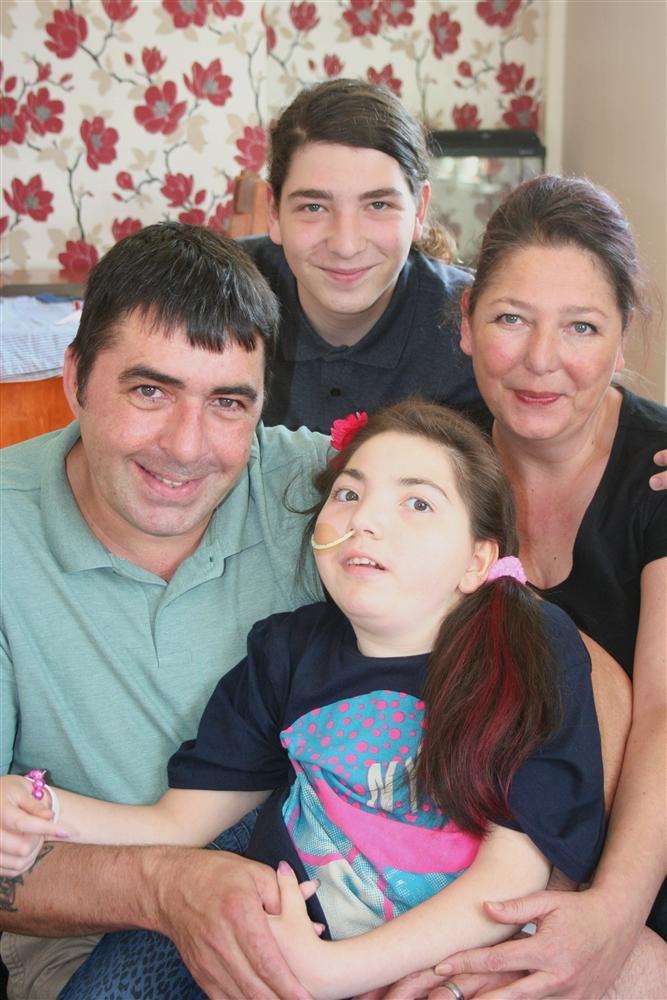 Isidora Dyer, 14, who is fighting severely debilitating Rett syndrome, and her mum Etta Bonugle, "dad" Andy Bonugli and brother Somerset, 17, at home in Minster