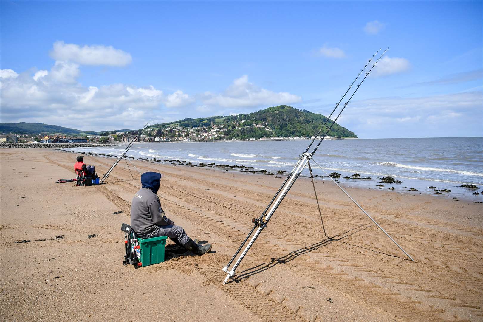 Two fishermen angle their rods towards the sea on the beach at Minehead (Ben Birchall/PA)