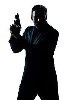 Silhouette picture of a man holding a gun like James Bond