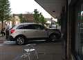 Woman taken to hospital after car hits shop